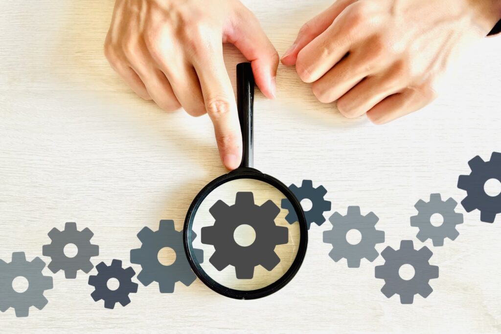 歯車が並んでいて、虫眼鏡で一個の歯車にフォーカスしている